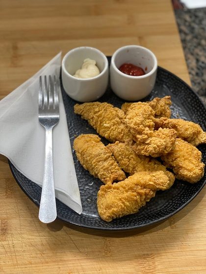 A plate of crispy chicken tenders with two dipping sauces