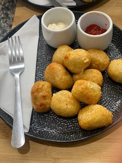 A plate of crispy chilli cheese bites with two dipping sauces